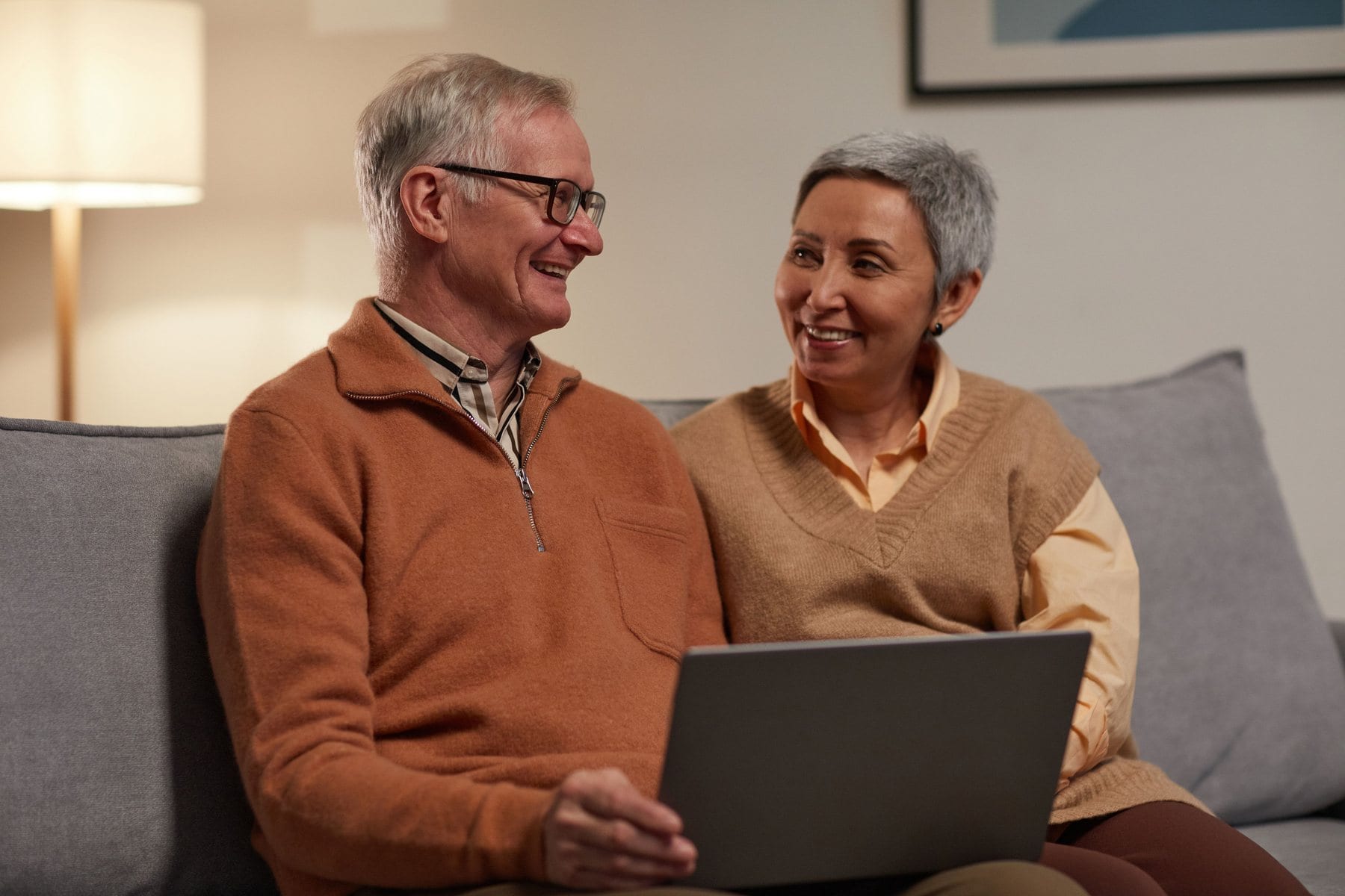 A couple smiling together over a laptop at home