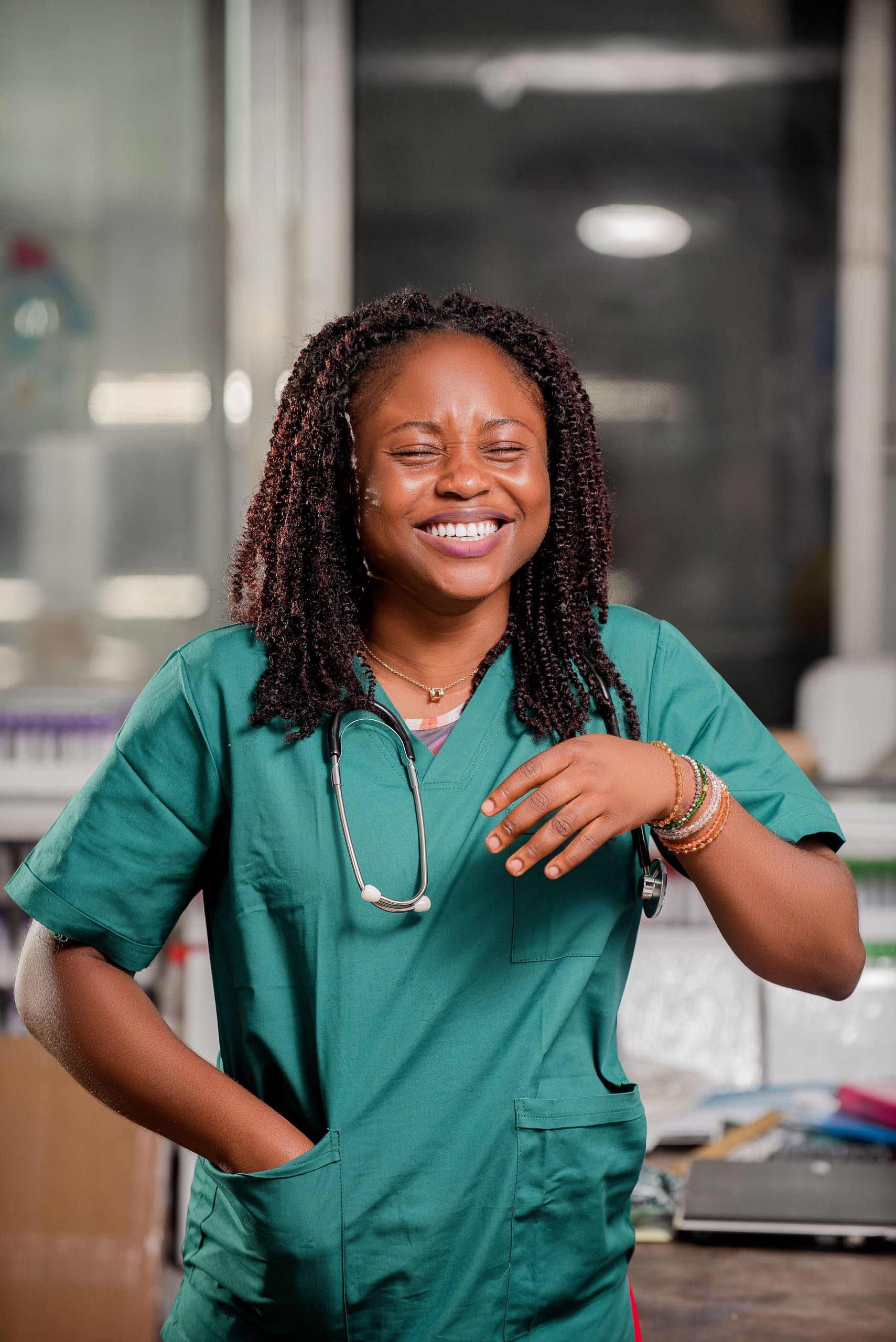 A nurse in green scrubs laughing in a clinic