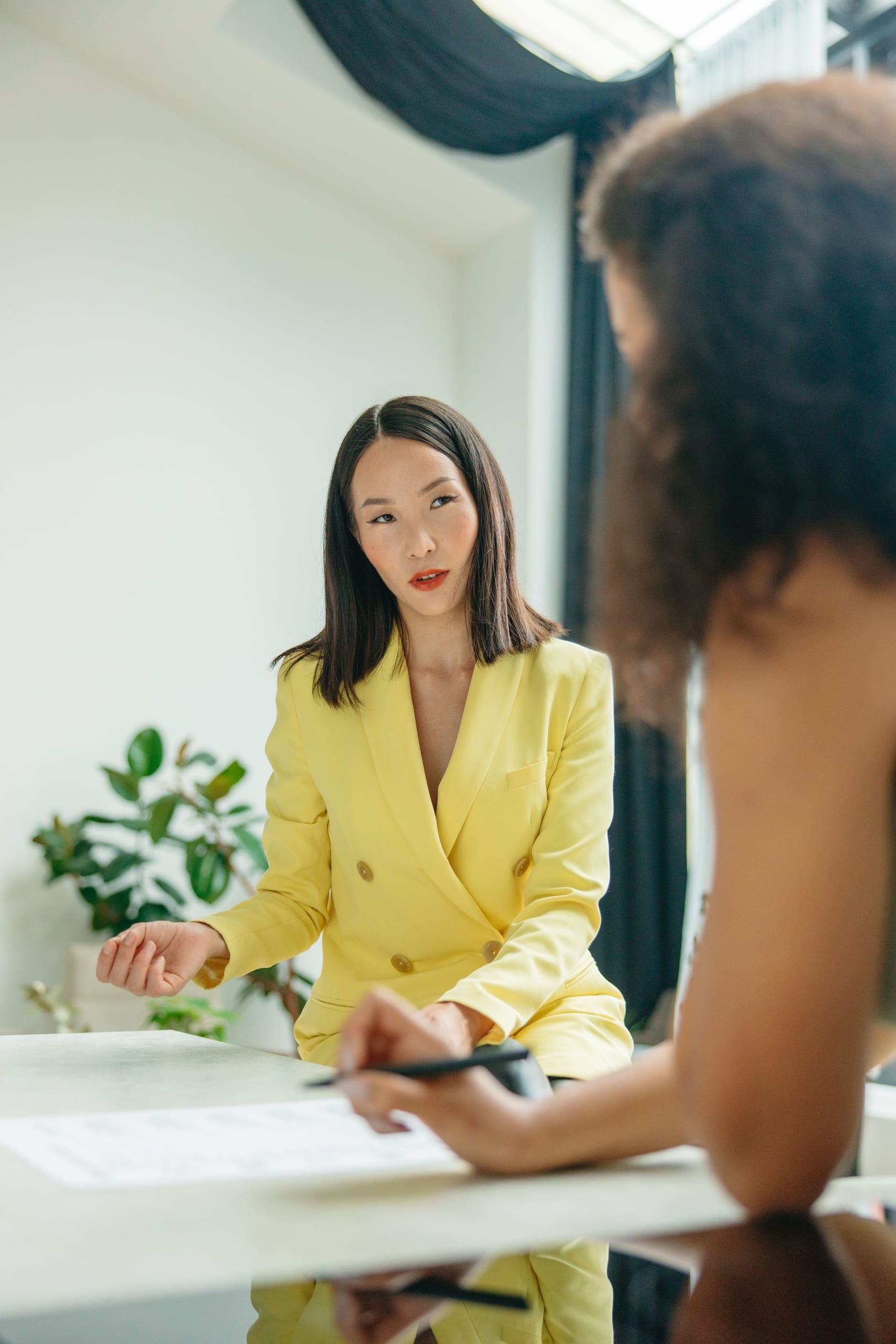 Two women talking across a table in a bright office