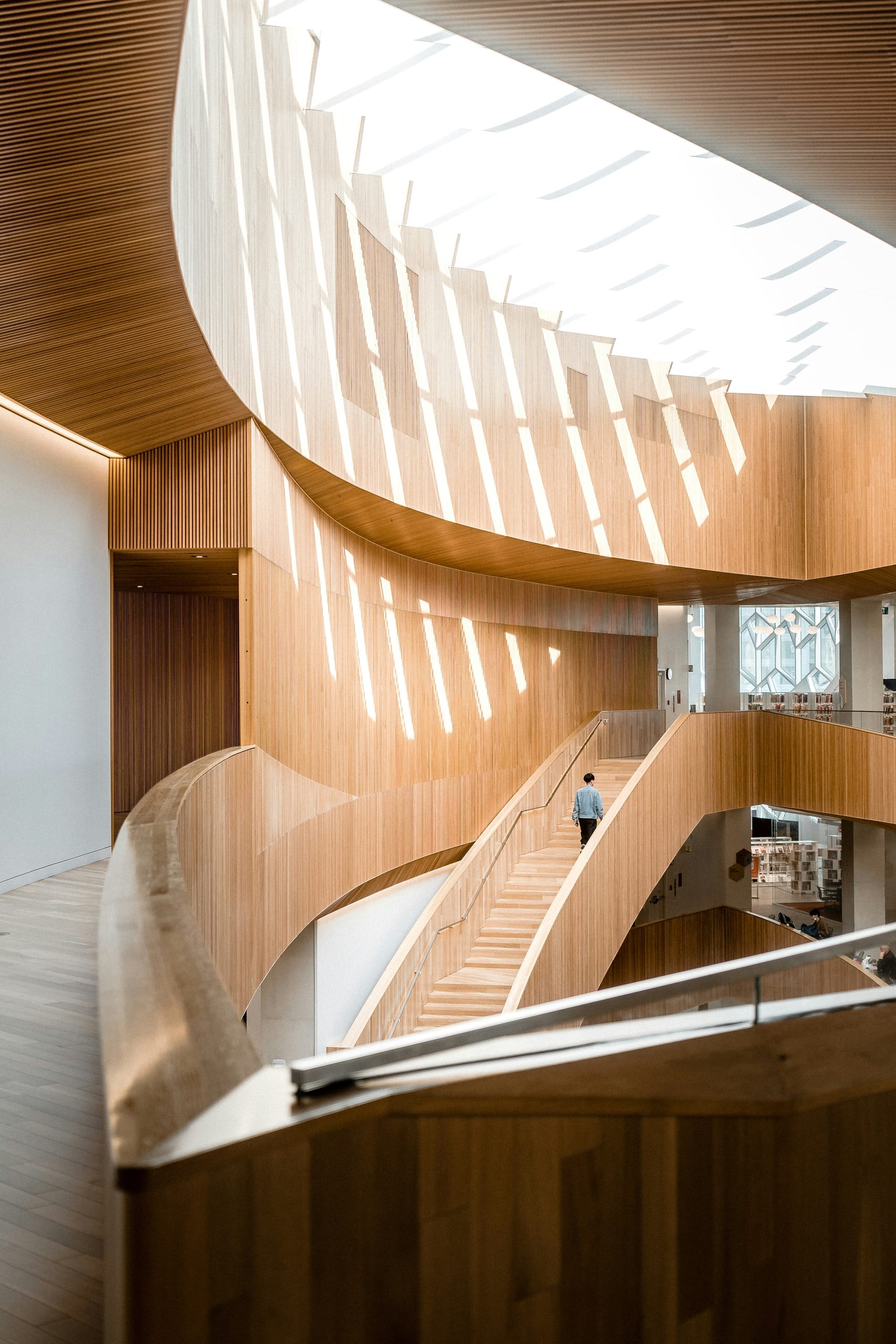 A lone figure climbing a sweeping staircase