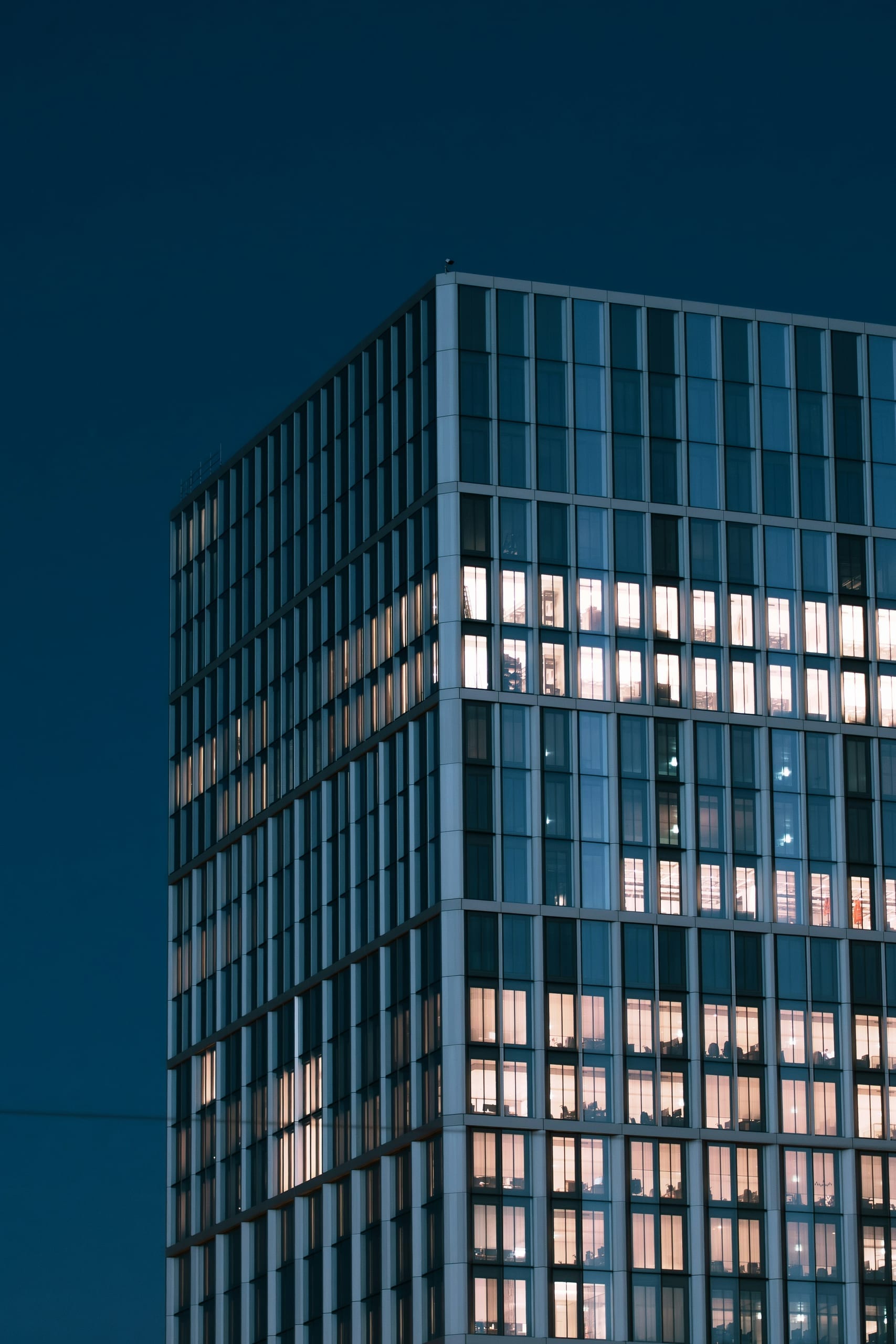 A glass tower lit against an evening sky